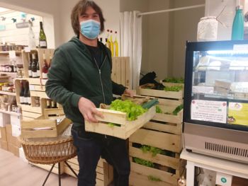 Photo d'une personne masquée qui prend une cagette pleine de légumes